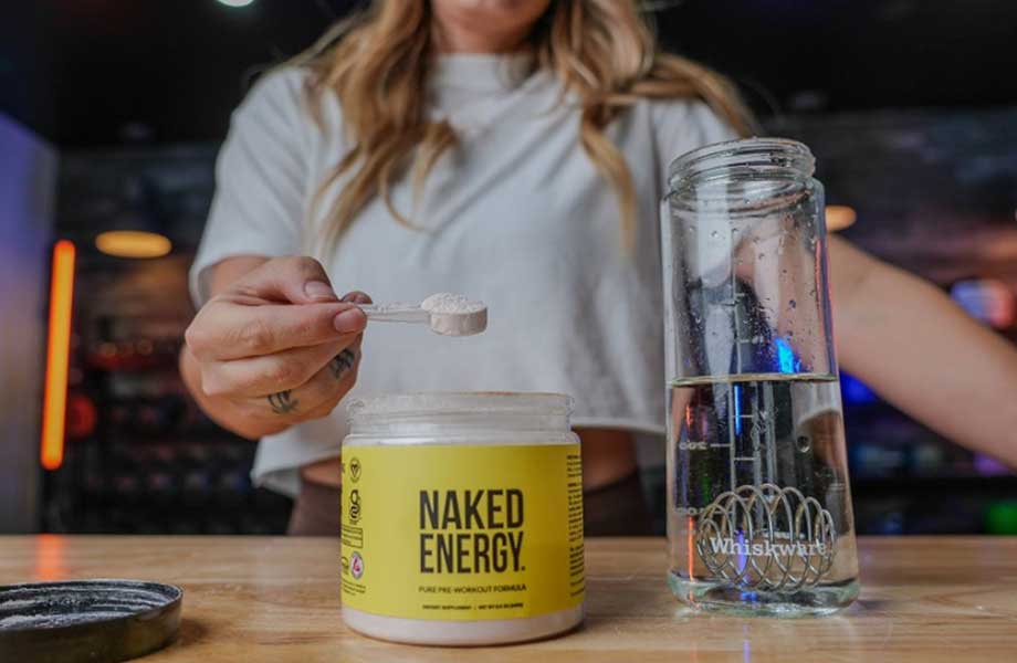 Woman scooping Naked Pre-workout out of container