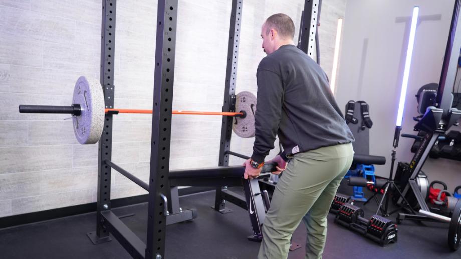 Man rolling the Nike weight bench into a squat cage
