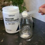 Someone scooping Nutricost creatine into a shaker glass