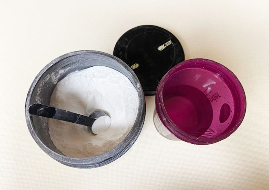 An open tub of Optimum Nutrition BCAA next to a shaker bottle