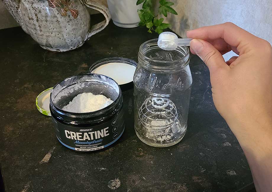 scooping Onnit creatine into a glass