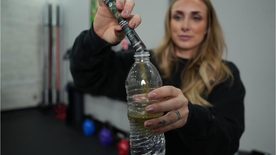 An image of a woman mixing Onnit Shroom Tech Greens