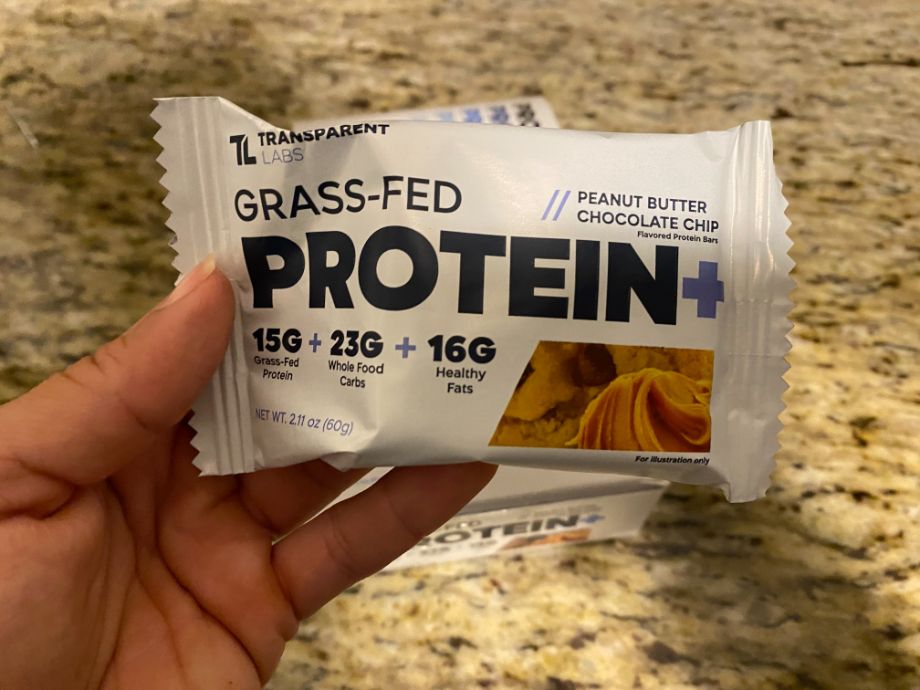 A hand holds a packaged Transparent Labs Protein bar