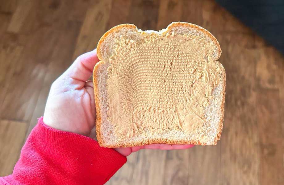 Someone holding a piece of bread with PB&Me spread on it