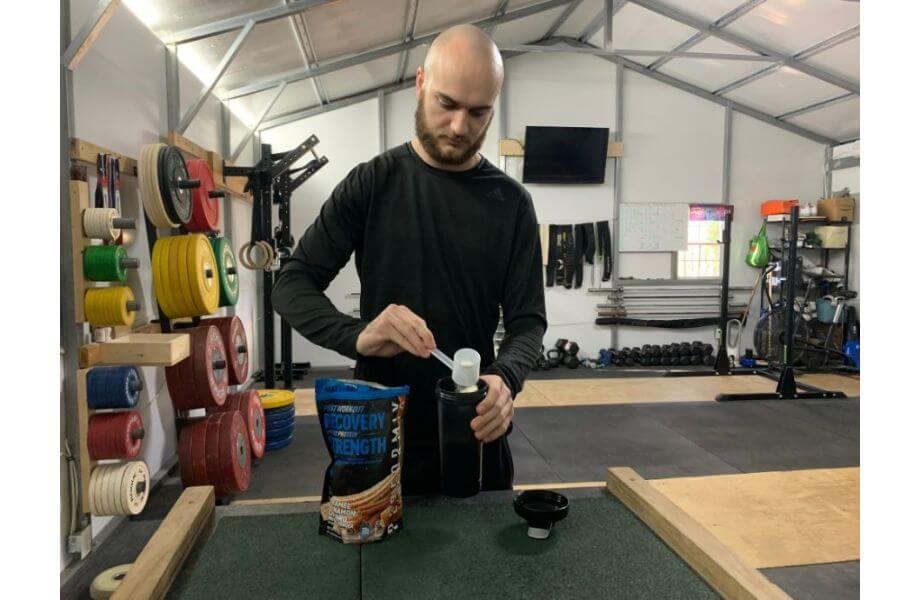 man standing at desk scooping powder from bottle performix protein powder