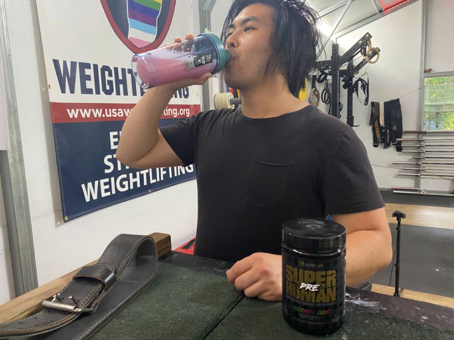 Person drinking Alpha Lion Superhuman Pre-Workout in a gym