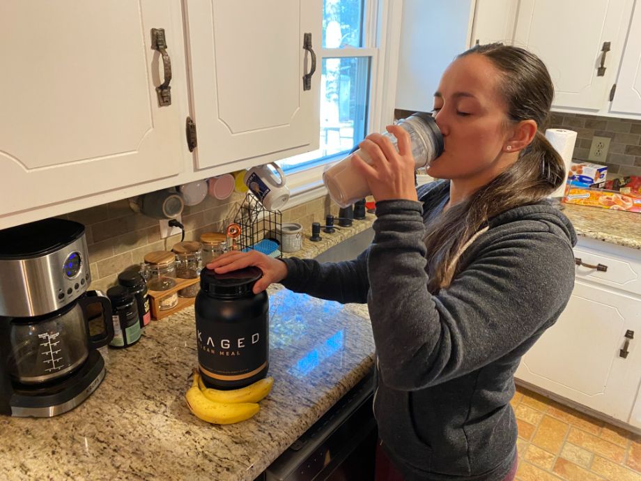 Woman drinking Kaged Clean Muscle out of a shaker bottle