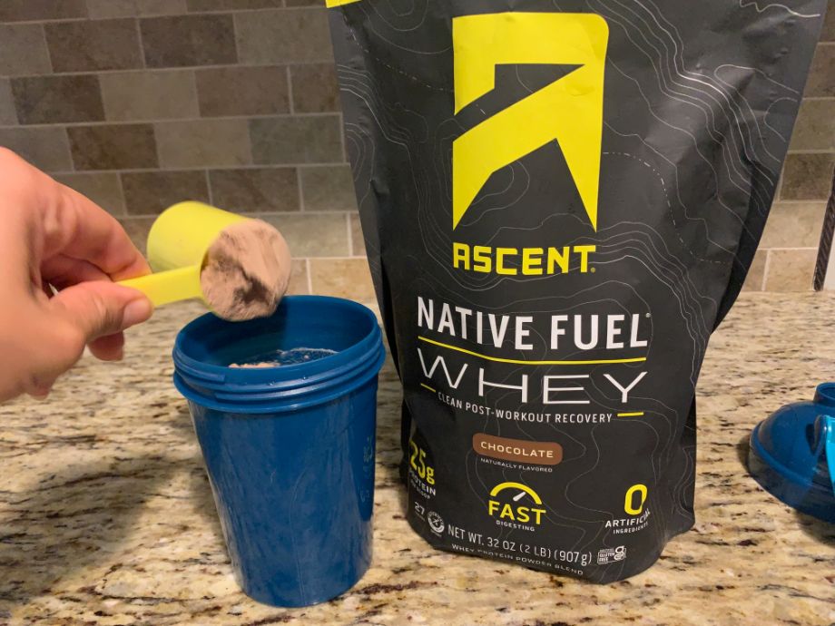 Person pouring a scoop of Ascent  Whey Protein