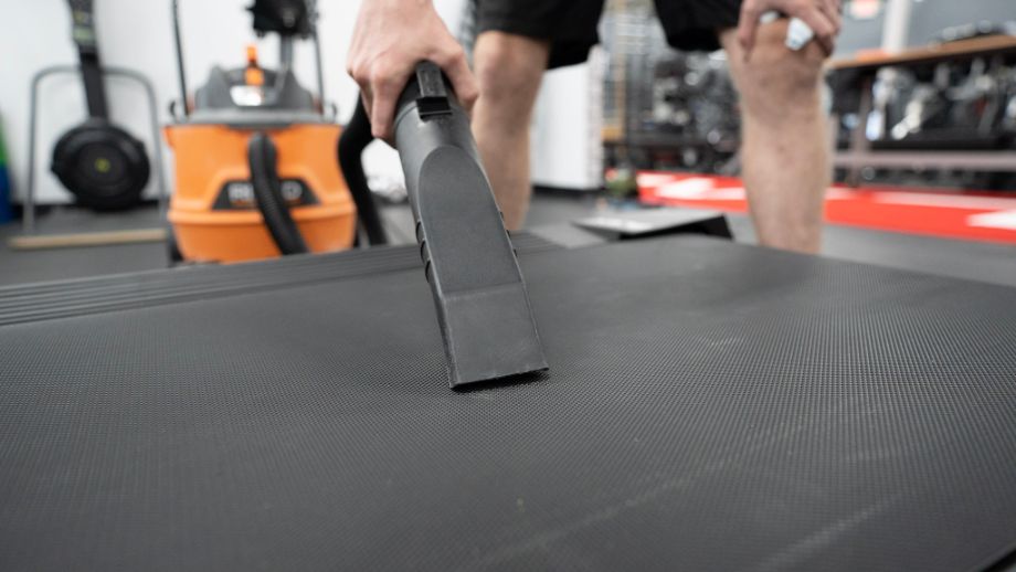 Person vacuuming treadmill belt