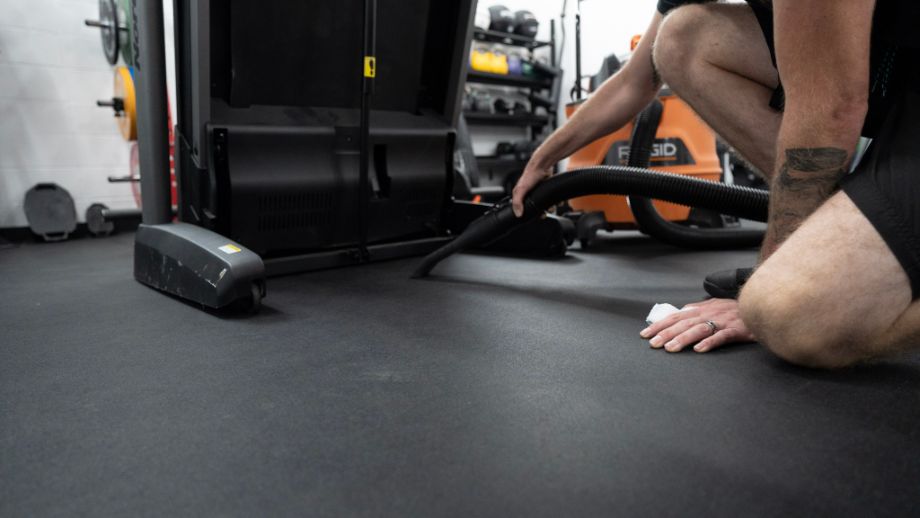 Person vacuuming under treadmill