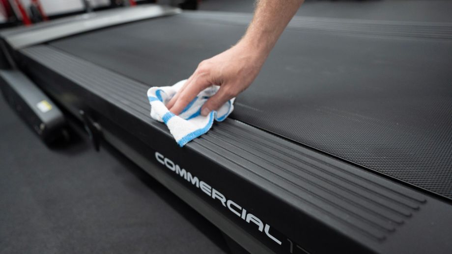 Person wiping down treadmill belt