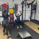 personal trainer instructing overhead press