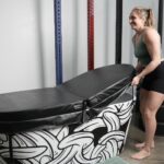 A person is shown taking the lid off of a Polar Monkeys cold plunge tub.