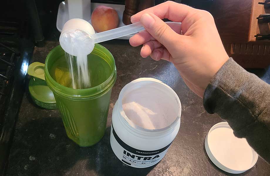 Someone dumping a scoop of Transparent Labs Intra into a shaker bottle