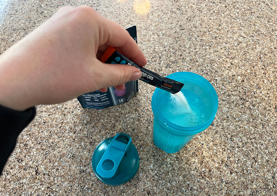 Looking down into shaker bottle while a packet of DripDrop ORS is poured in.