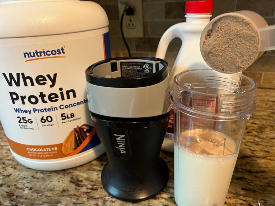 Pouring Nutricost Whey Concentrate into a cup