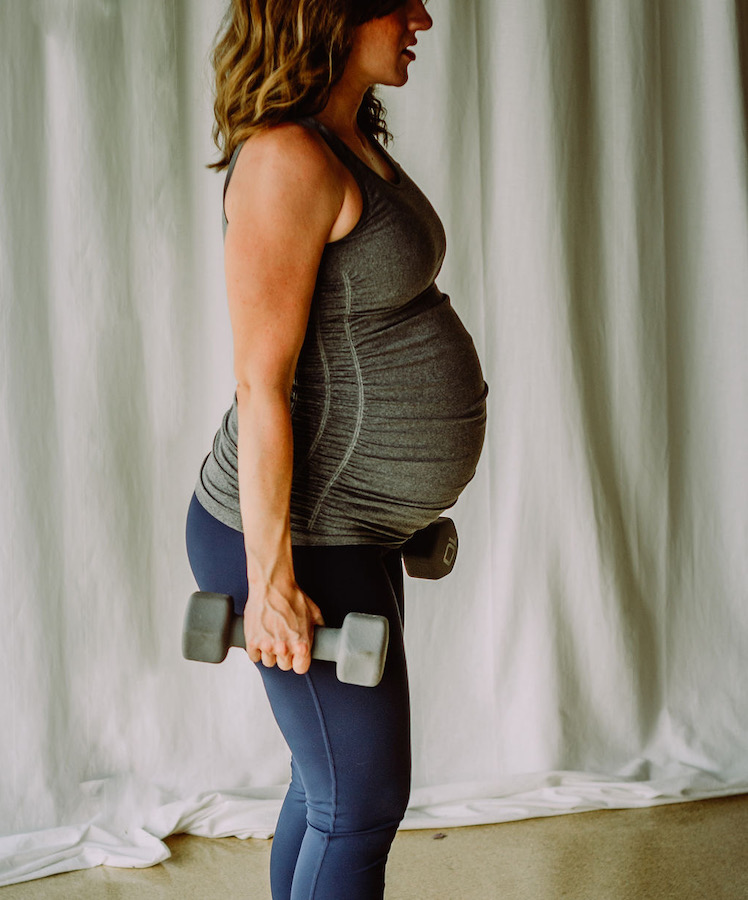 An image of a pregnant woman with dumbbells