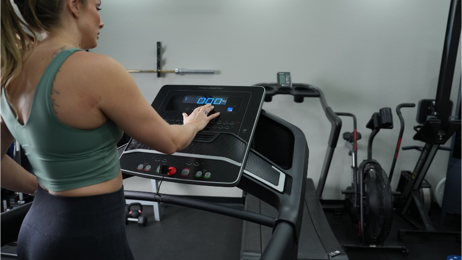 An image of a woman pressing buttons on the ProForm TLX console