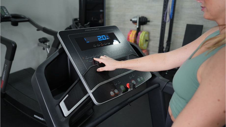 An image of a woman adjusting the speed on the ProForm TLX treadmill