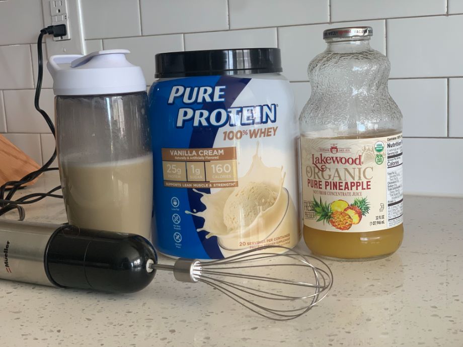Pure Protein on counter next to juice and mixer
