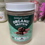 A container of Purely Inspired Organic Protein on a kitchen counter.