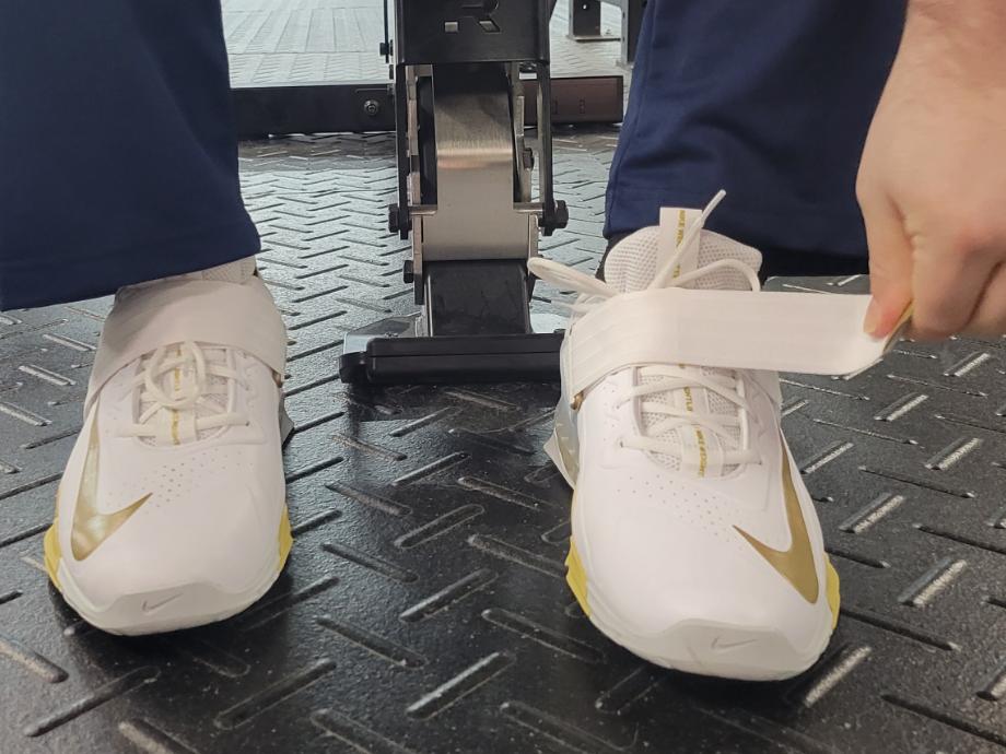 Close look at a person strapping into the Nike Savaleos weightlifting shoes.