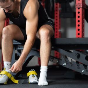 Man putting on Nike Savaleos weightlifting shoes before a workout