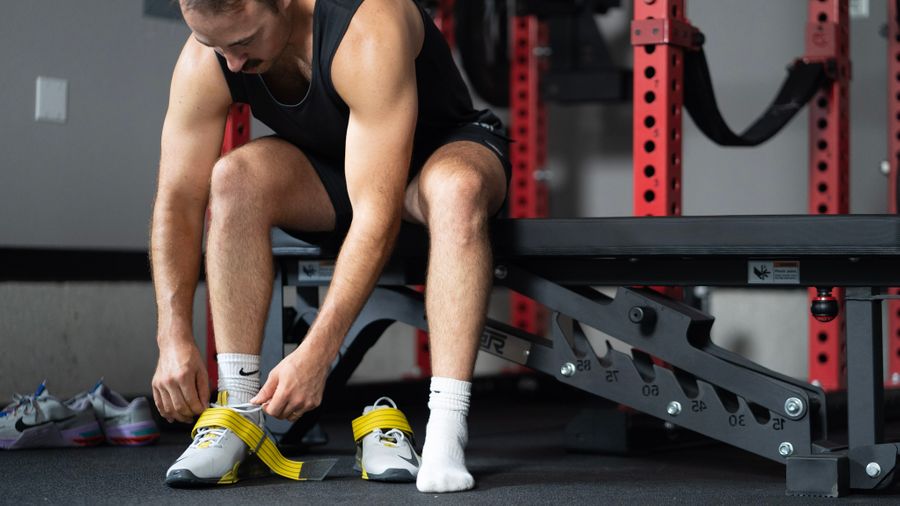 Man putting on Nike Savaleos weightlifting shoes before a workout