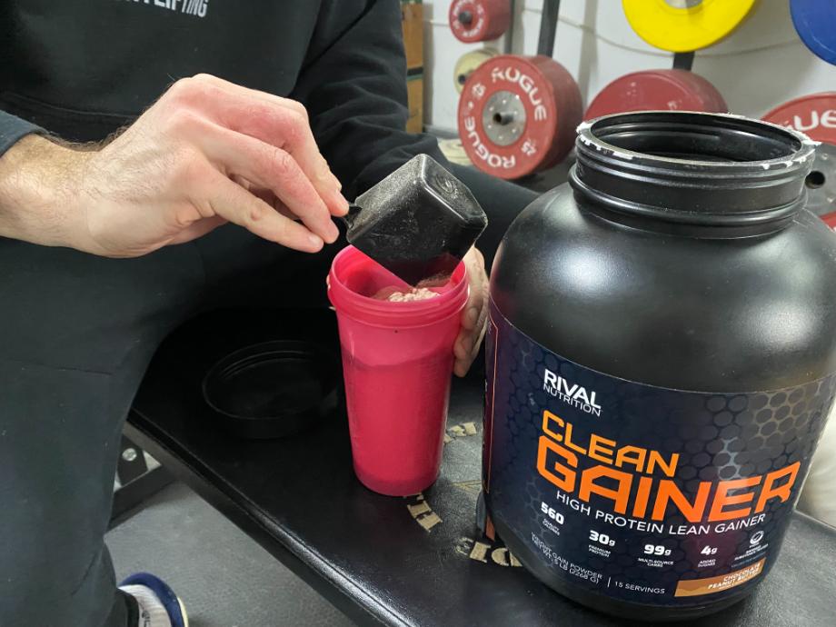 A close view of a shaker cup just after dumping in a huge scoop of Rival Nutrition Clean Gainer.