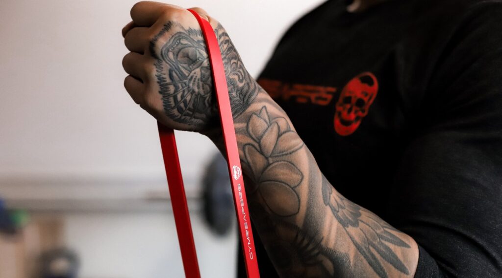 Person using red Gymreapers Resistance Band around hand.