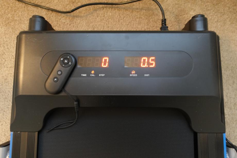 Looking down on the front end of a REDLIRO Under Desk Treadmill, with remote and displey console showing.