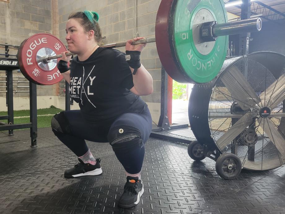 A woman does a back squat with Reebok Lifter PR 3 shoes.