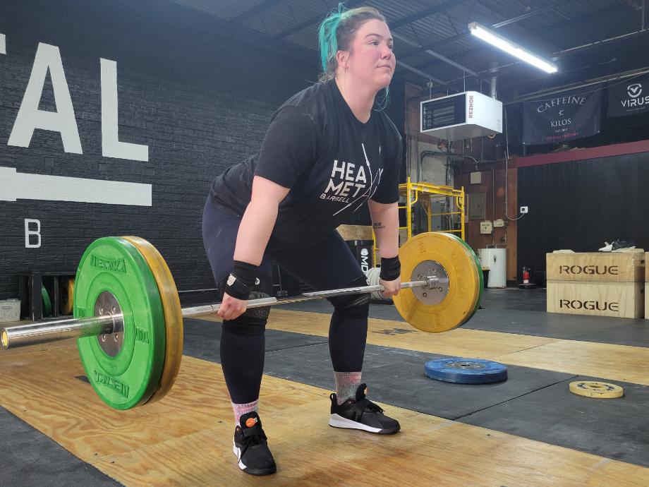 A woman doing a clean pull while wearing Reebok Lifter PR 3 shoes.