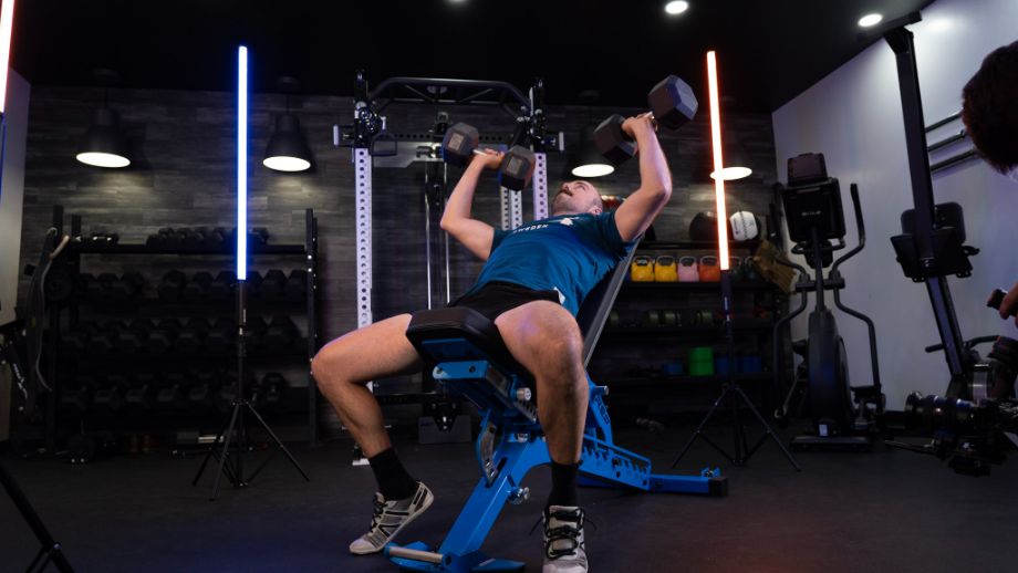 Man performing dumbbell incline bench press on the REP Fitness Blackwing