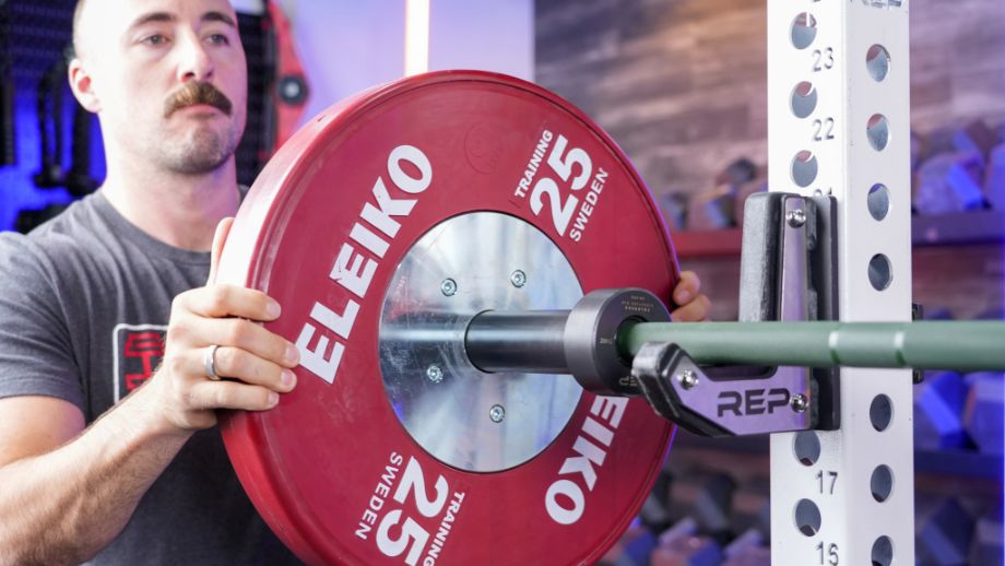 Man loading a bumper plate onto the REP Fitness Colorado Bar