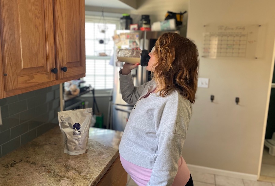 An image of a woman drinking Ritual Essential protein powder for pregnancy