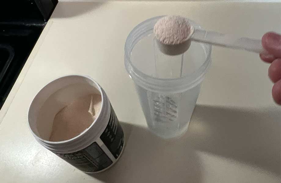 A scoop of El Jefe Pre-Workout is about to be poured into a shaker cup.