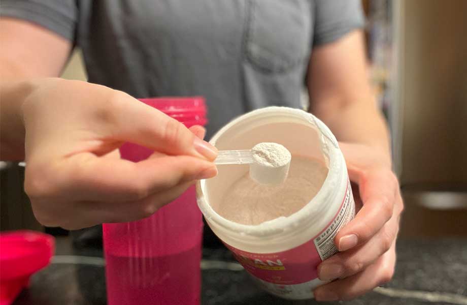 Close-up of a person holding up a scoop of AminoLean Pre-Workout
