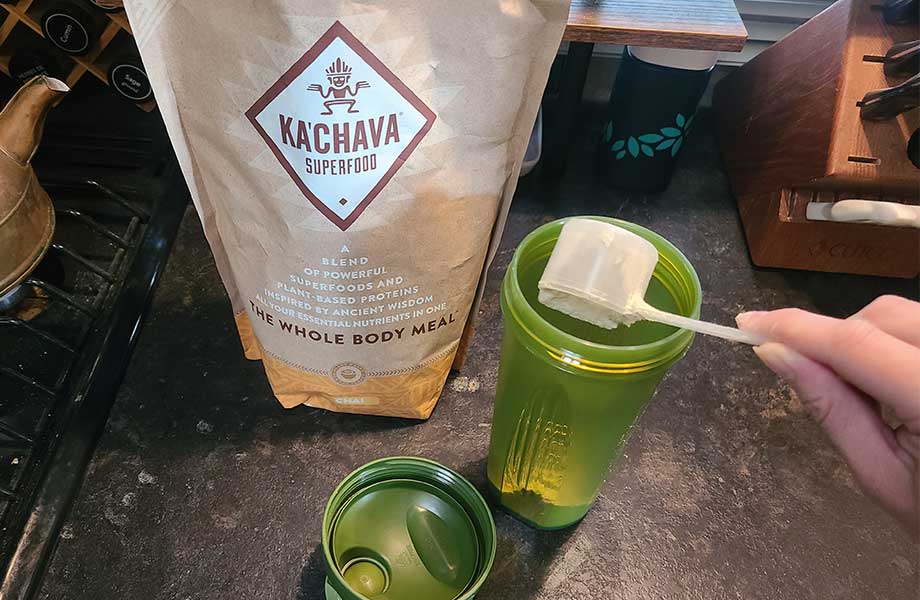 Someone scooping KaChava into a shaker bottle