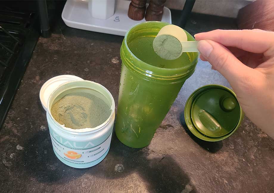 Scooping Kiala Greens Into A Shaker Bottle