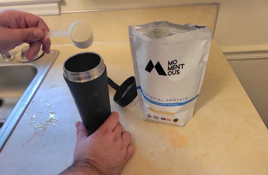 Hands are shown making a shake with Momentous Grass-Fed Whey Protein.