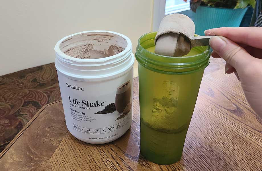 Someone scooping Shaklee soy protein into a shaker