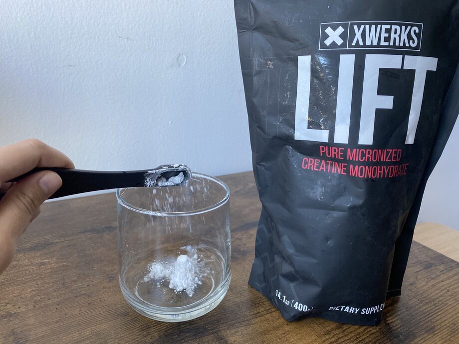 A scoop of XWERKS Lift Creatine being poured into a glass
