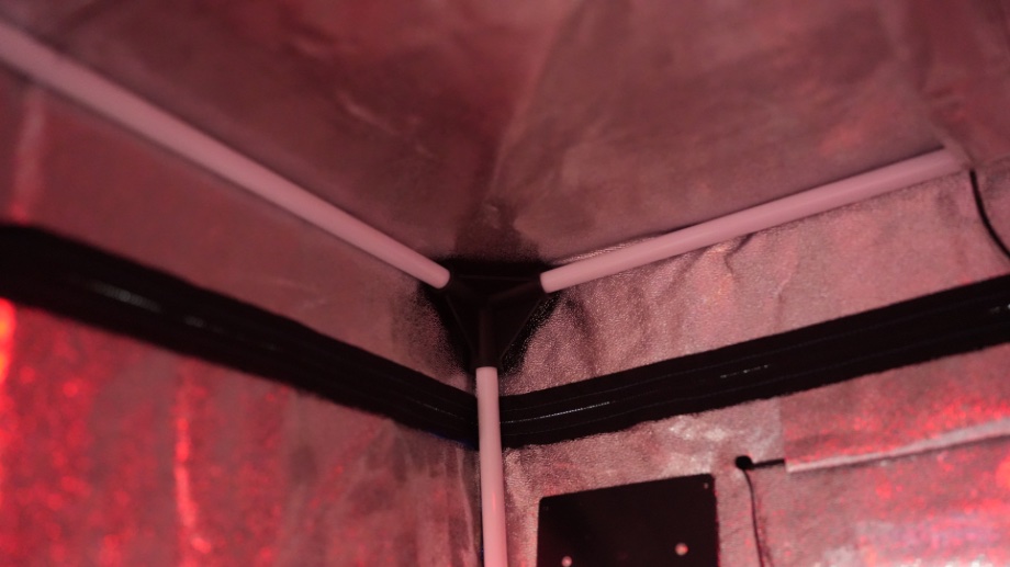 A view of the interior corner construction of a SereneLife Full Size Portable Infrared Sauna. The structural corner is a molded piece of plastic with white metal pipes inserted into it along the lines of the tent edges.