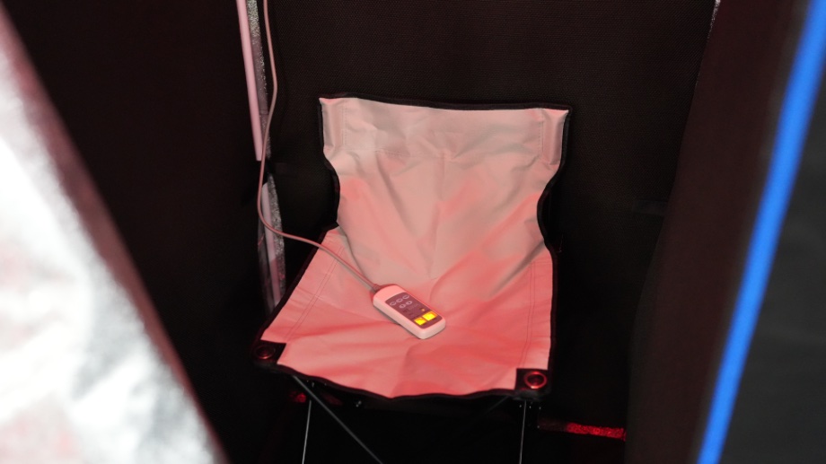 Looking into the SereneLife Full Size Portable Infrared Sauna at the wired remote and what looks like a white canvas camping chair. 