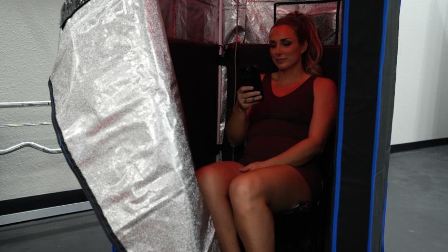 Woman sitting in the SereneLife Full-Size Portable Sauna with the door unzipped and open