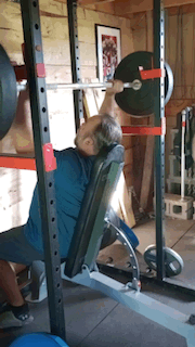 Man doing a shoulder press on a bench in the squat rack