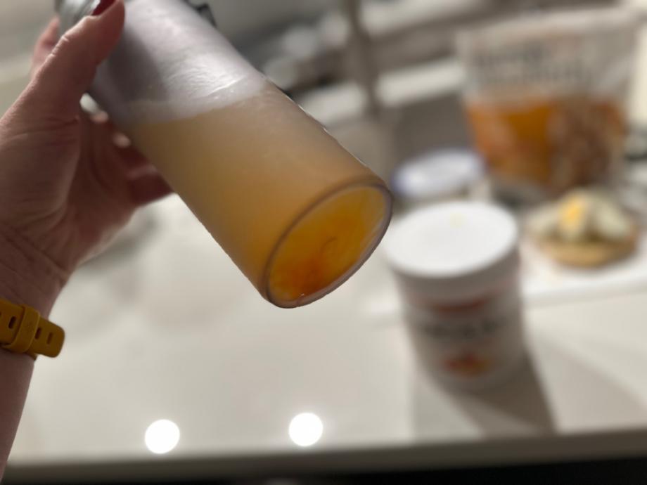 A woman shaking a mixed drink of Snap Supplements BCAA Powder with the container in the background on a counter