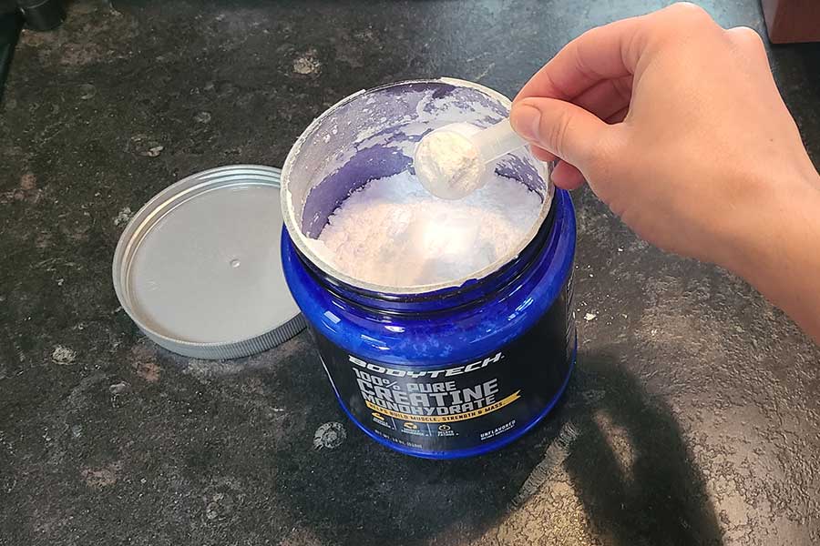 Someone Scooping Bodytech Creatine Out Of The Tub