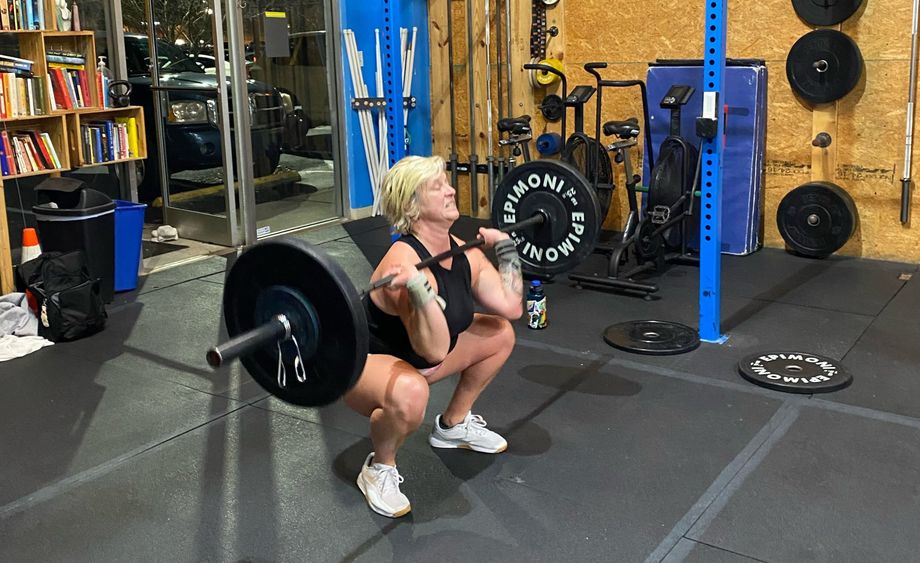 A woman performing front squats in a CrossFit gym